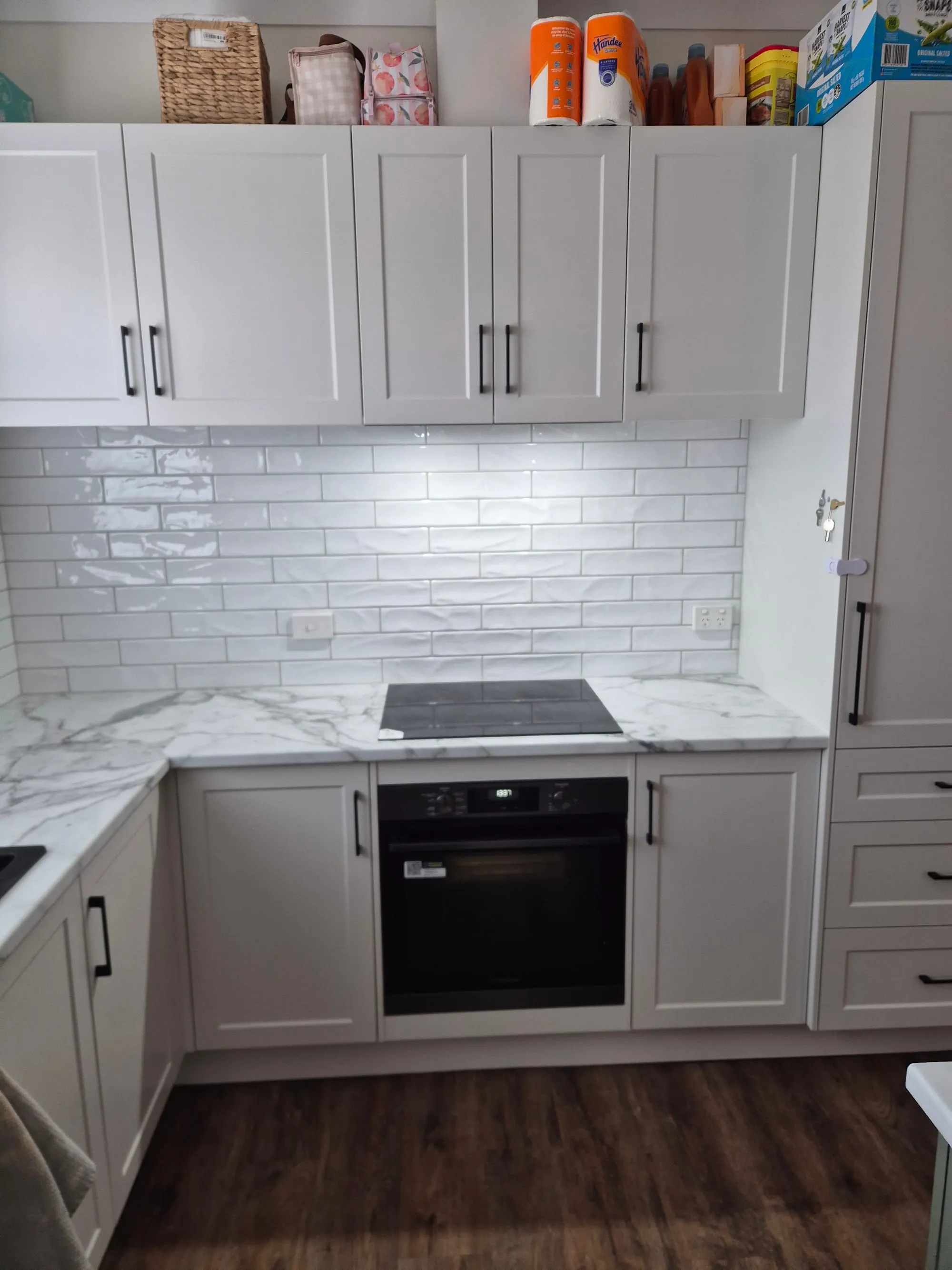 Kitchen with white cabinetry, a marble-look splashback and a built-in oven