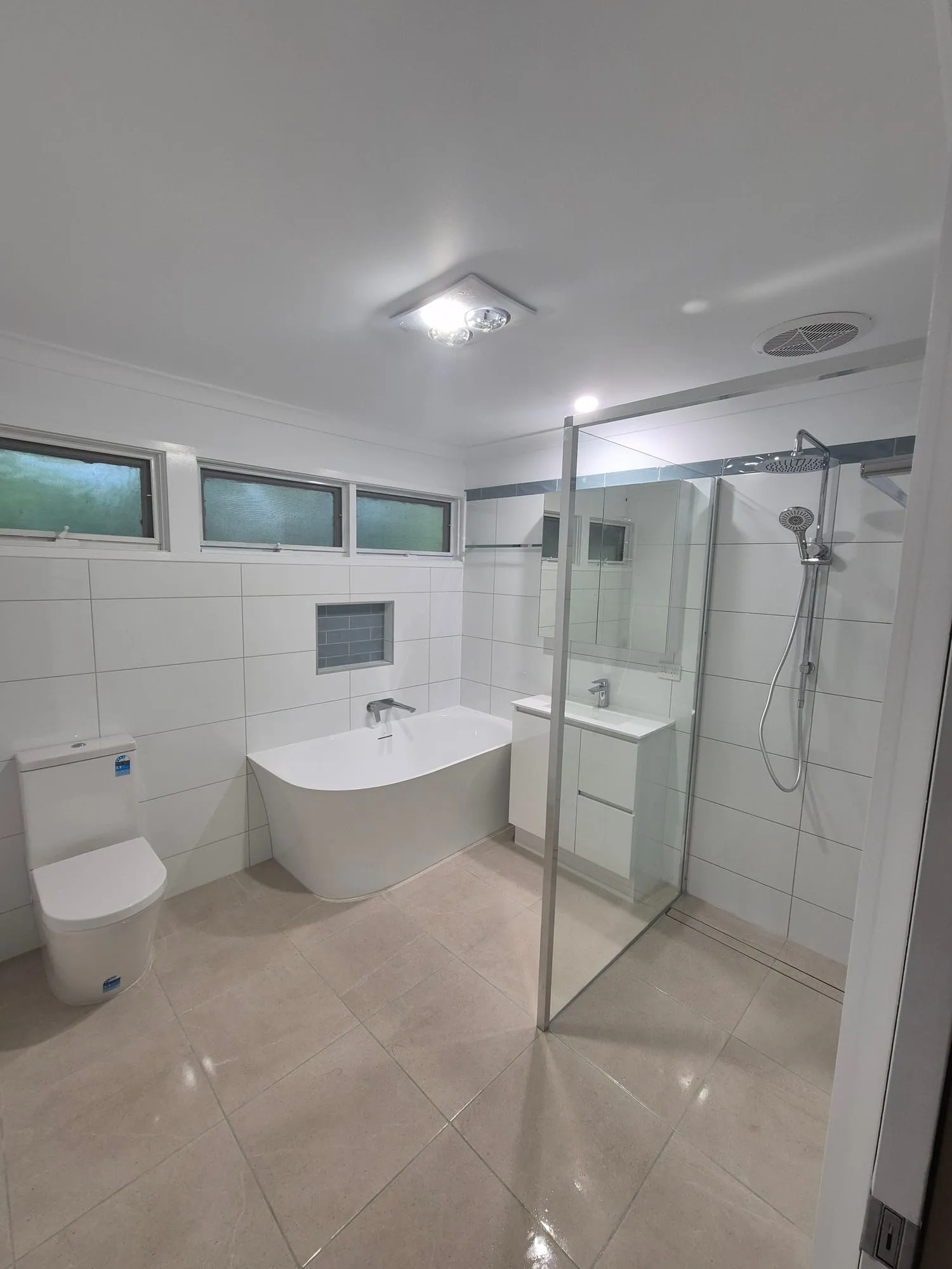 Bathroom with a vanity, mirror cabinet and a curbless shower behind a glass panel